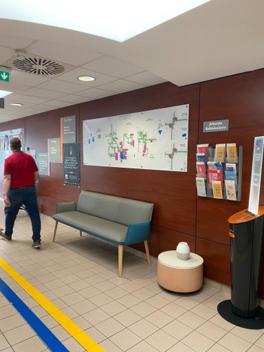 Un couloir avec un plan, un banc, un présentoir d'informations et des éléments de décoration.
